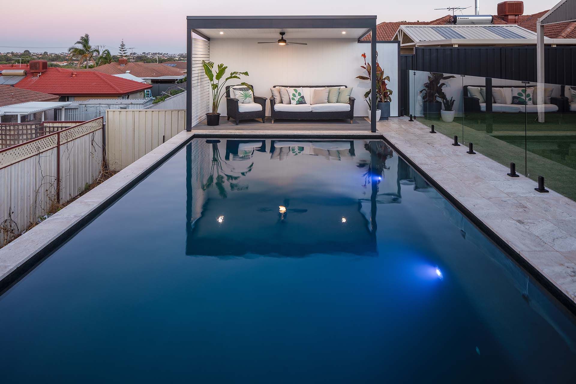 There is a large swimming pool in the backyard of a house.