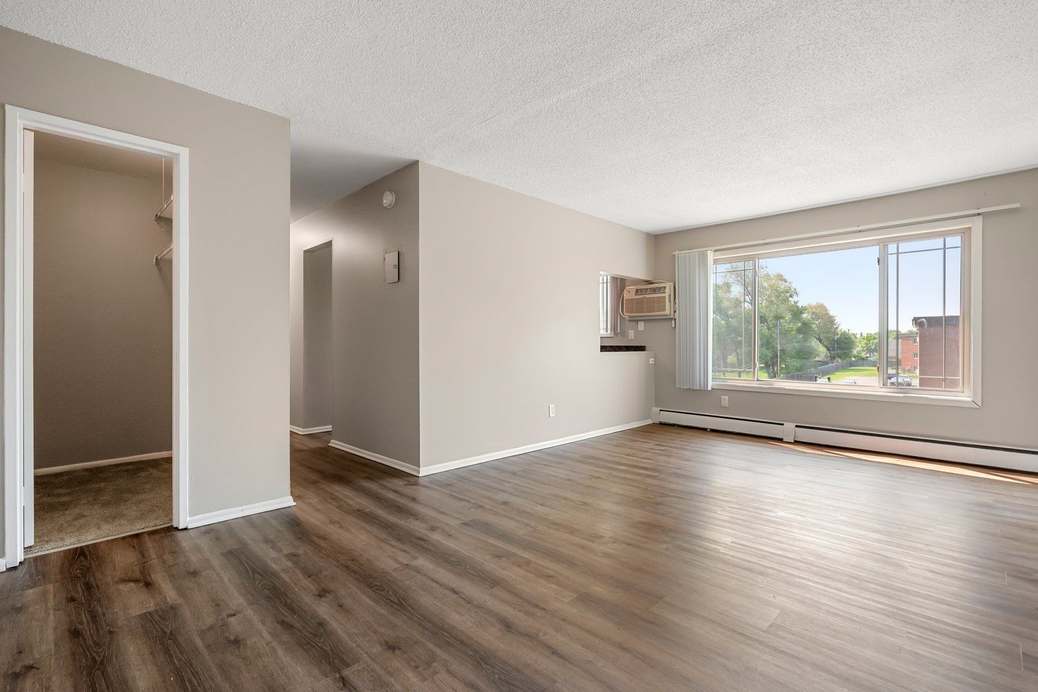 An empty living room with hardwood floors and a large window.