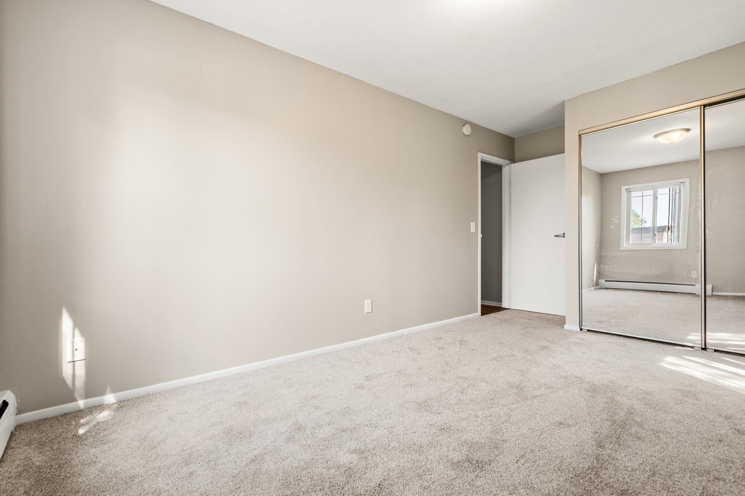 An empty bedroom with a sliding glass door and a window.