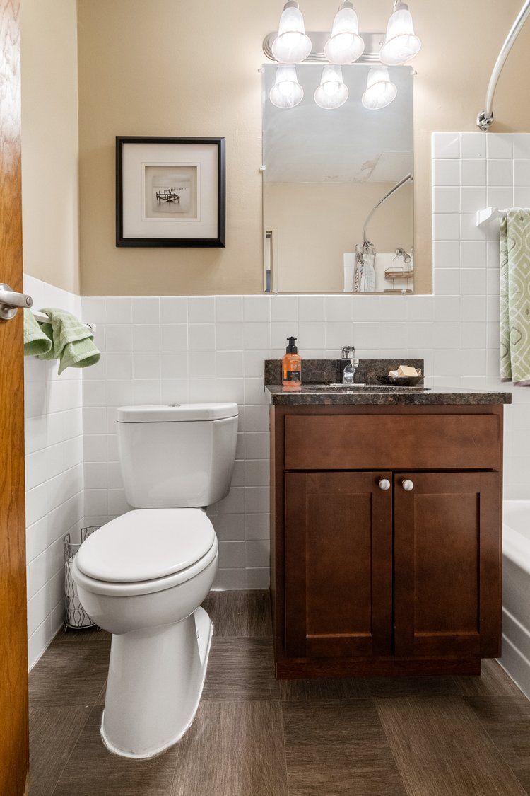 A bathroom with a toilet , sink , and mirror.