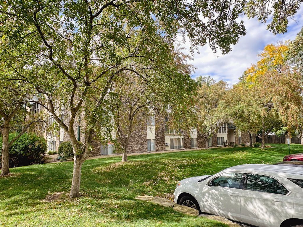 A white car is parked in front of a building in a park.