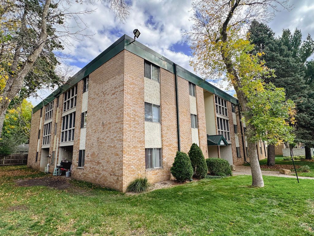 A large brick apartment building with a lot of windows and trees in front of it.