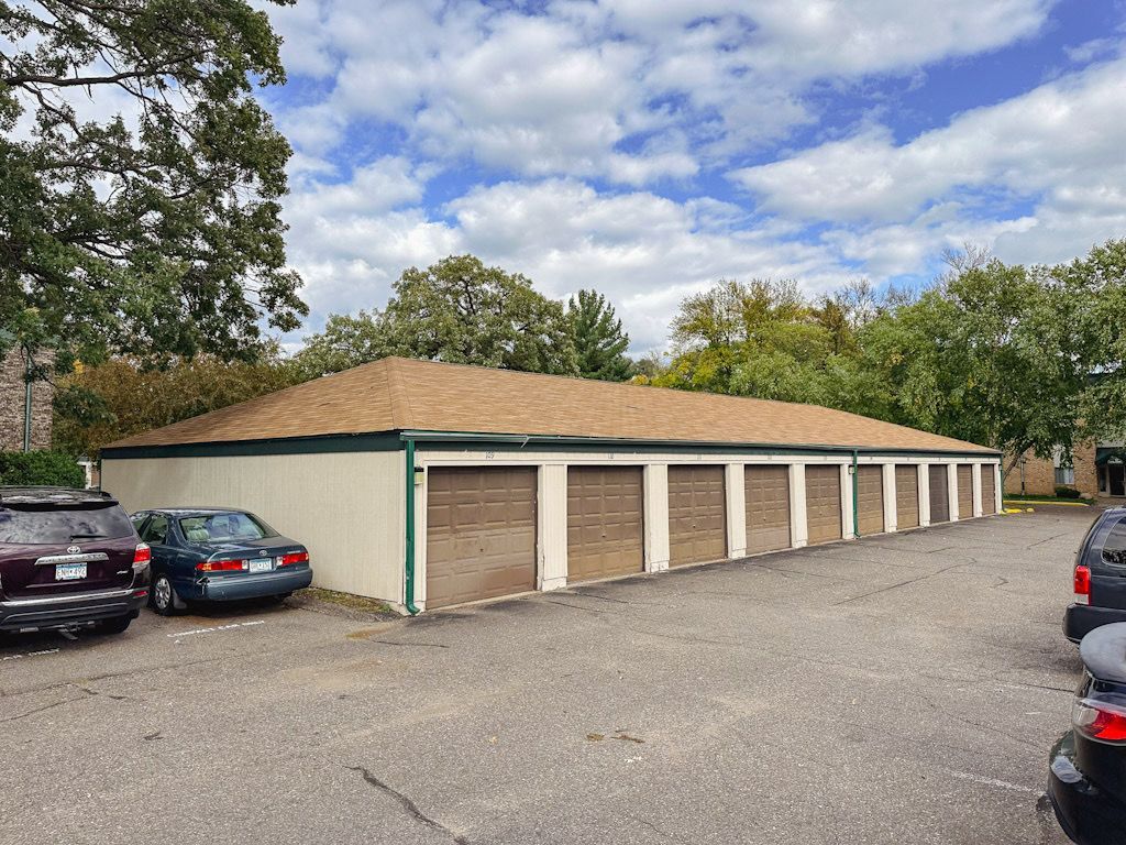 A row of garages with cars parked in front of them.
