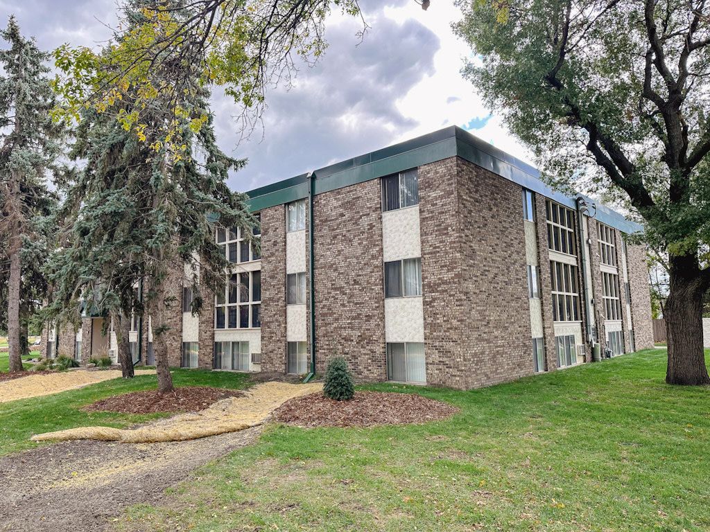 A large brick apartment building with trees in front of it.