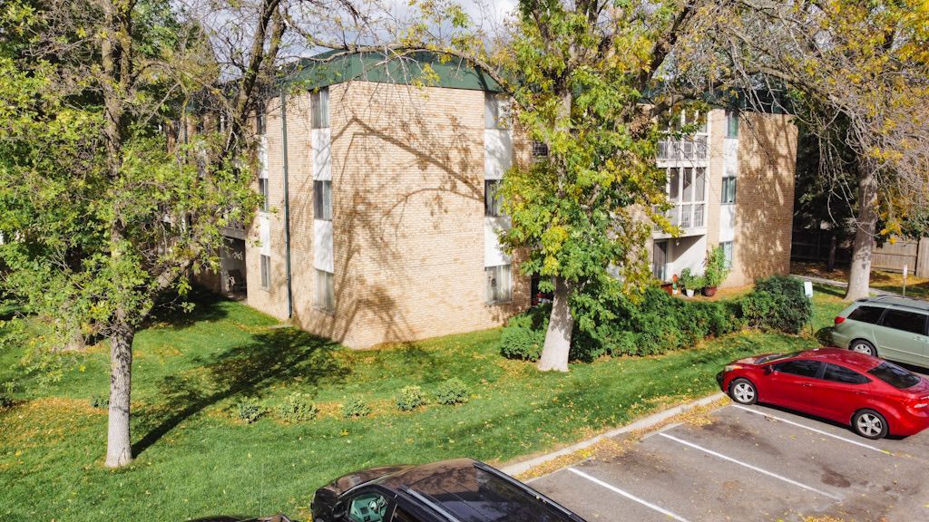 An aerial view of a apartment building with cars parked in front of it.