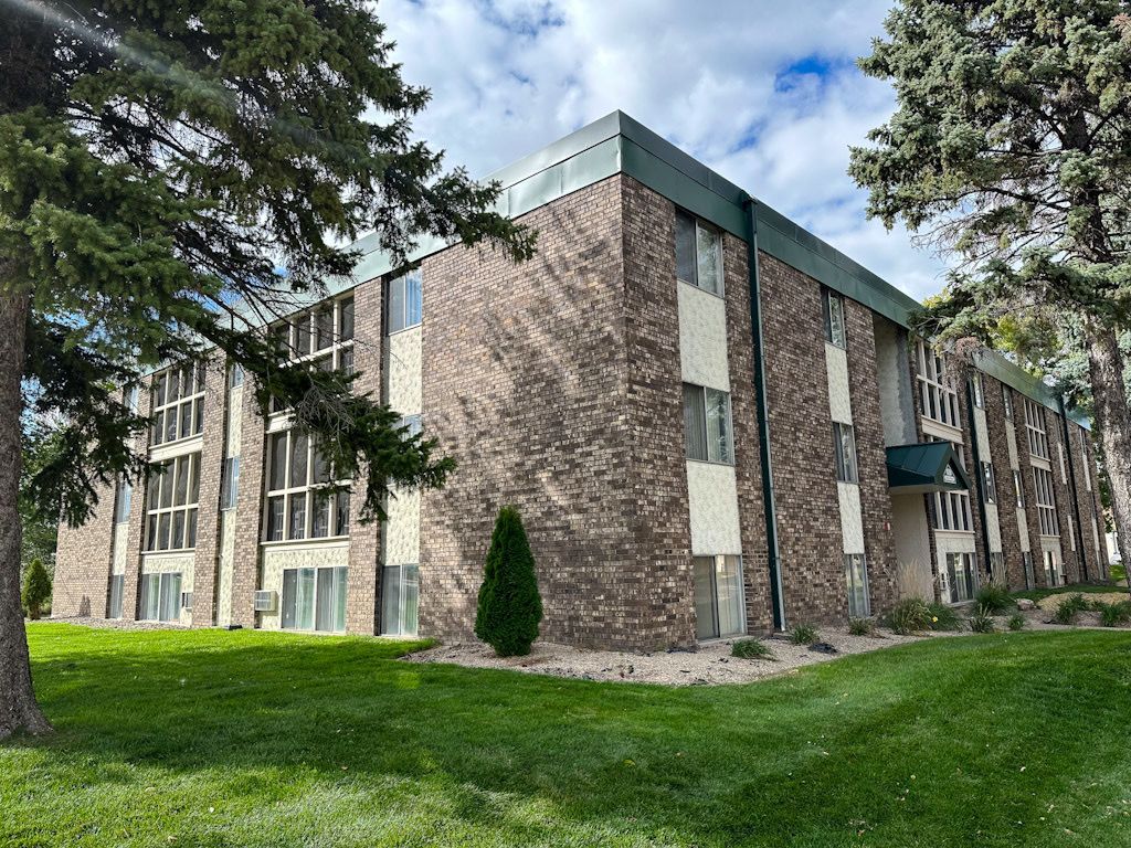 A large brick apartment building with a lot of windows and trees in front of it.