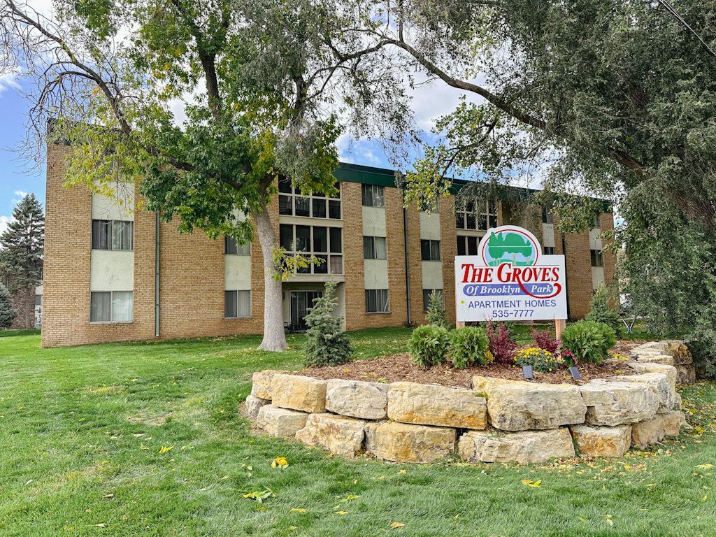 A large brick apartment building with a sign in front of it.