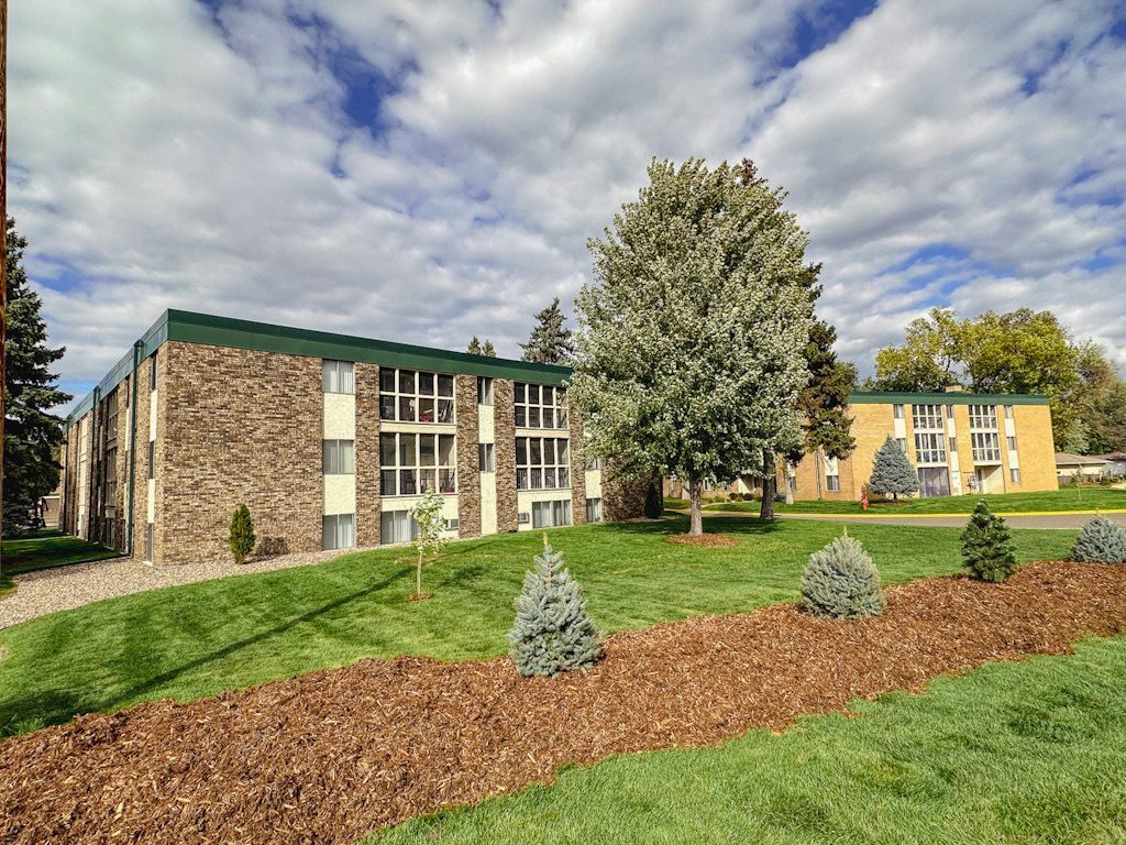 A large apartment building with a lot of windows and trees in front of it.