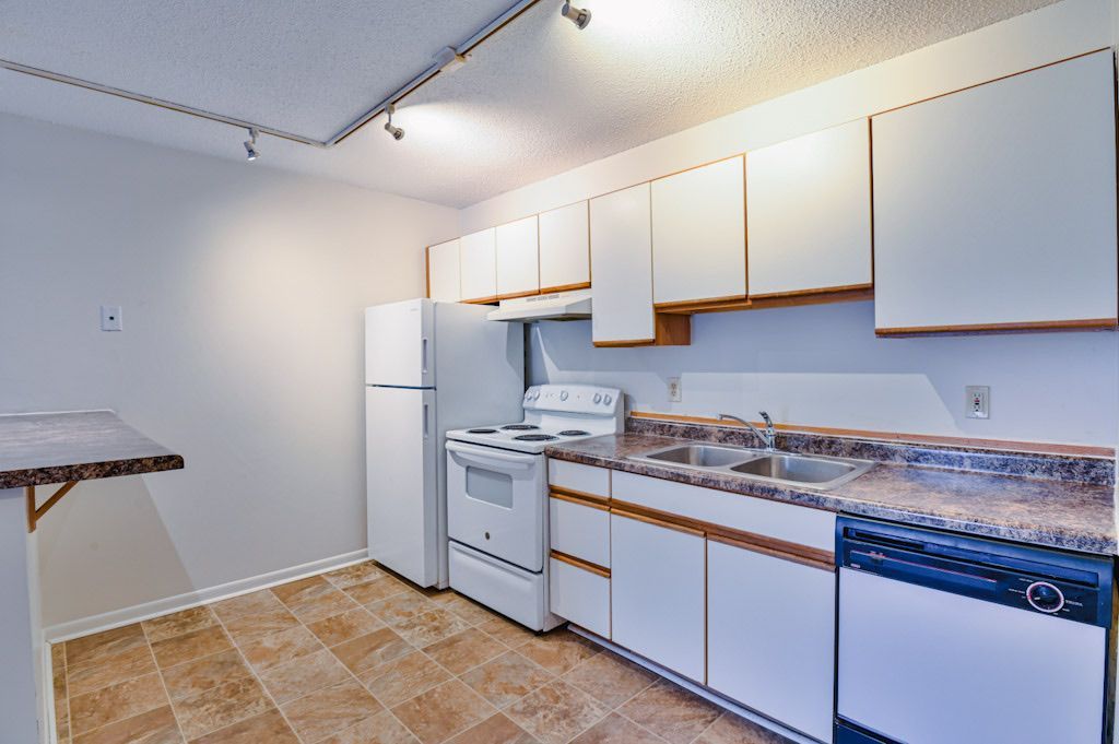 A kitchen with white cabinets and a stove and refrigerator
