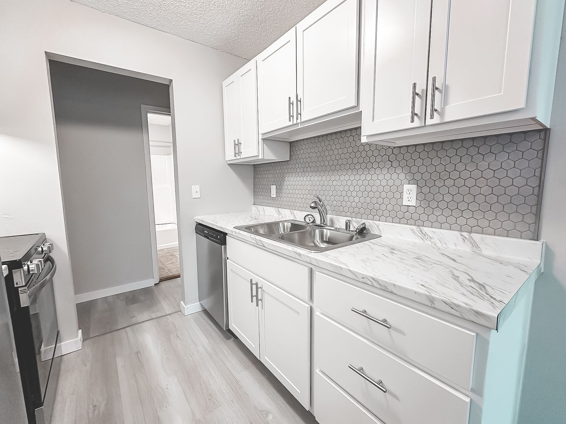A kitchen with white cabinets , a sink , and a stove.