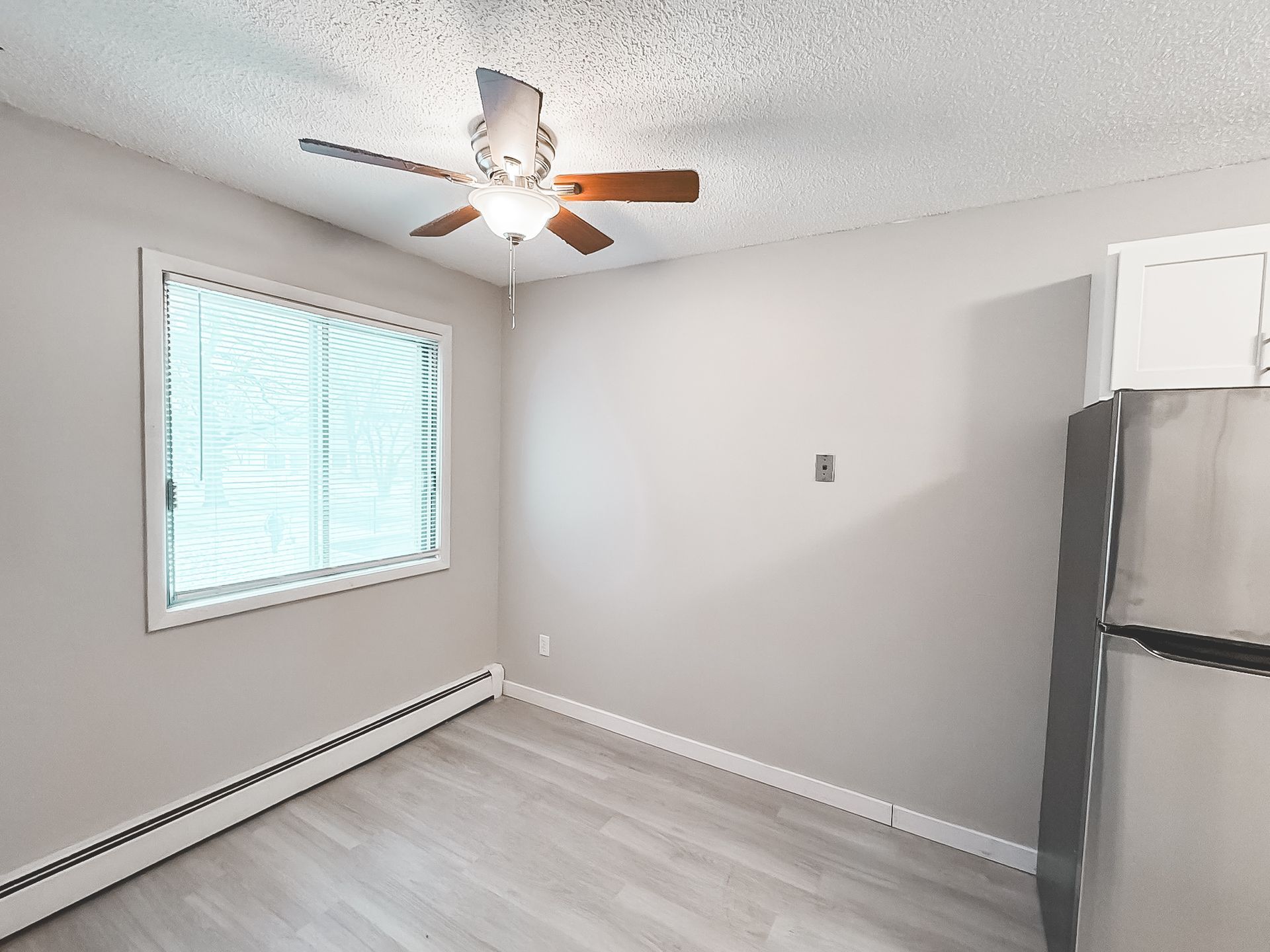 An empty room with a ceiling fan and a window