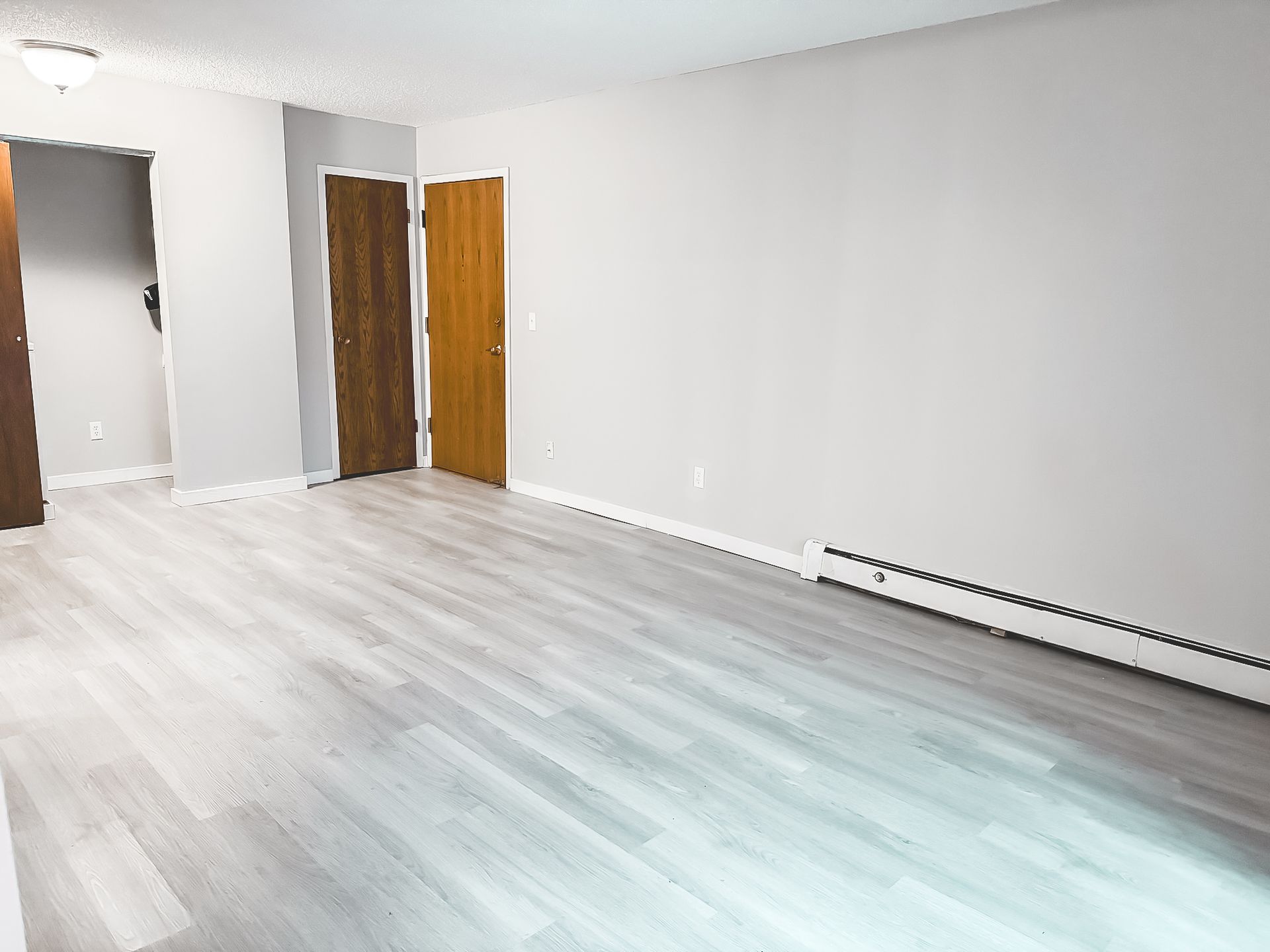 An empty living room with hardwood floors and white walls.