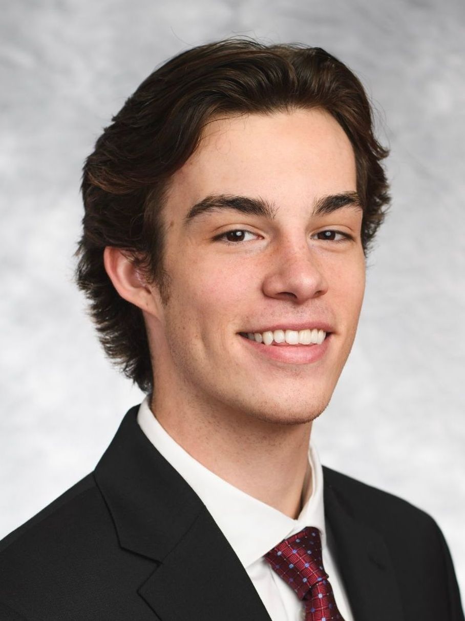 A young man in a suit and tie is smiling for the camera