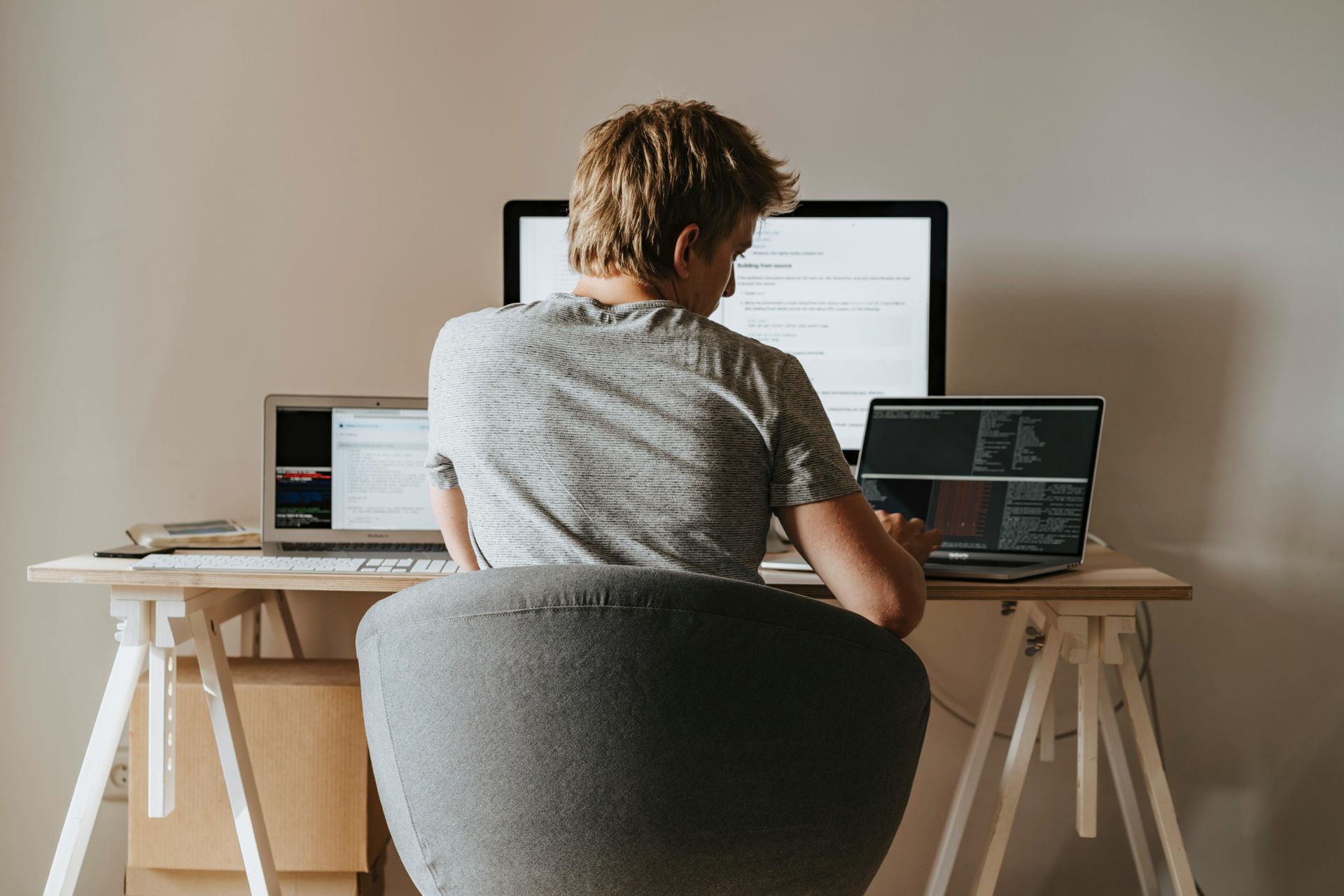 A man is sitting at a desk with a laptop and a computer.