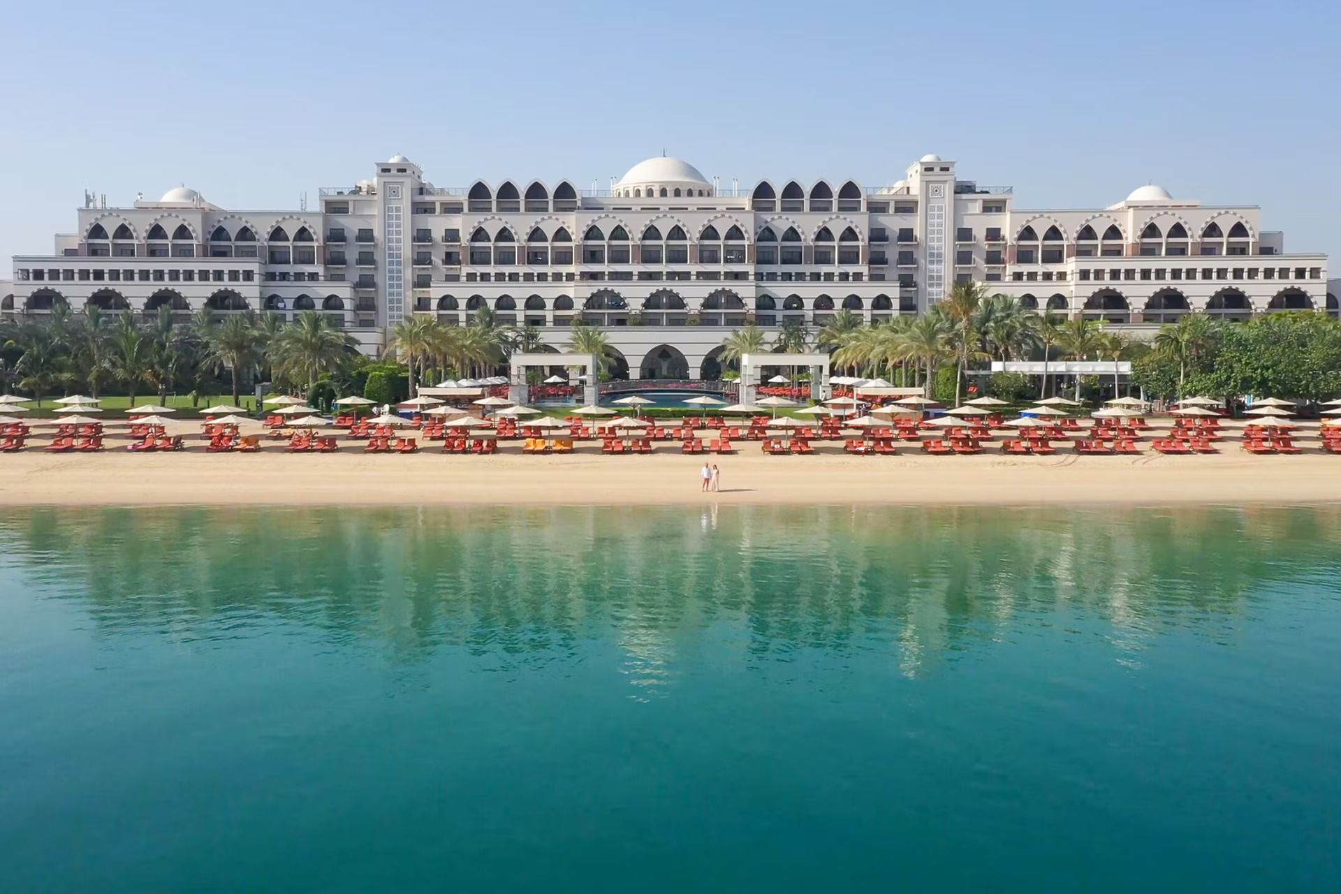 A large building is sitting on top of a beach next to a body of water.