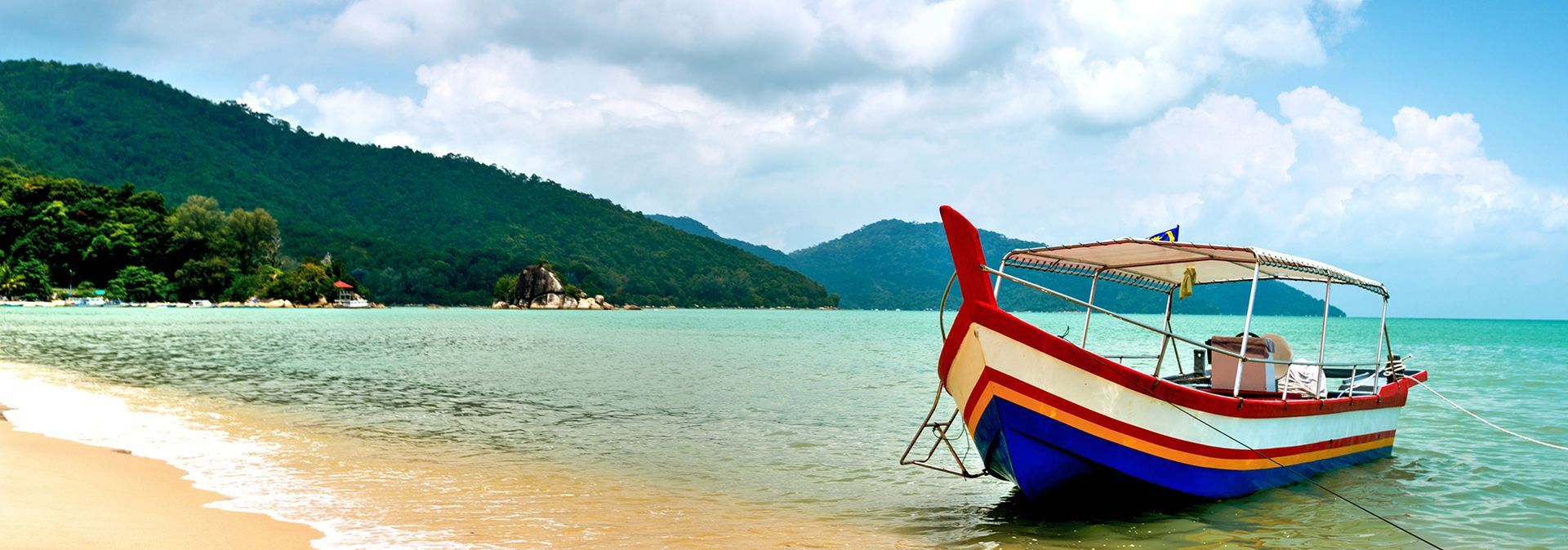 A boat resting on the shores of Batu Ferringhi Beach in Penang, Malaysia.