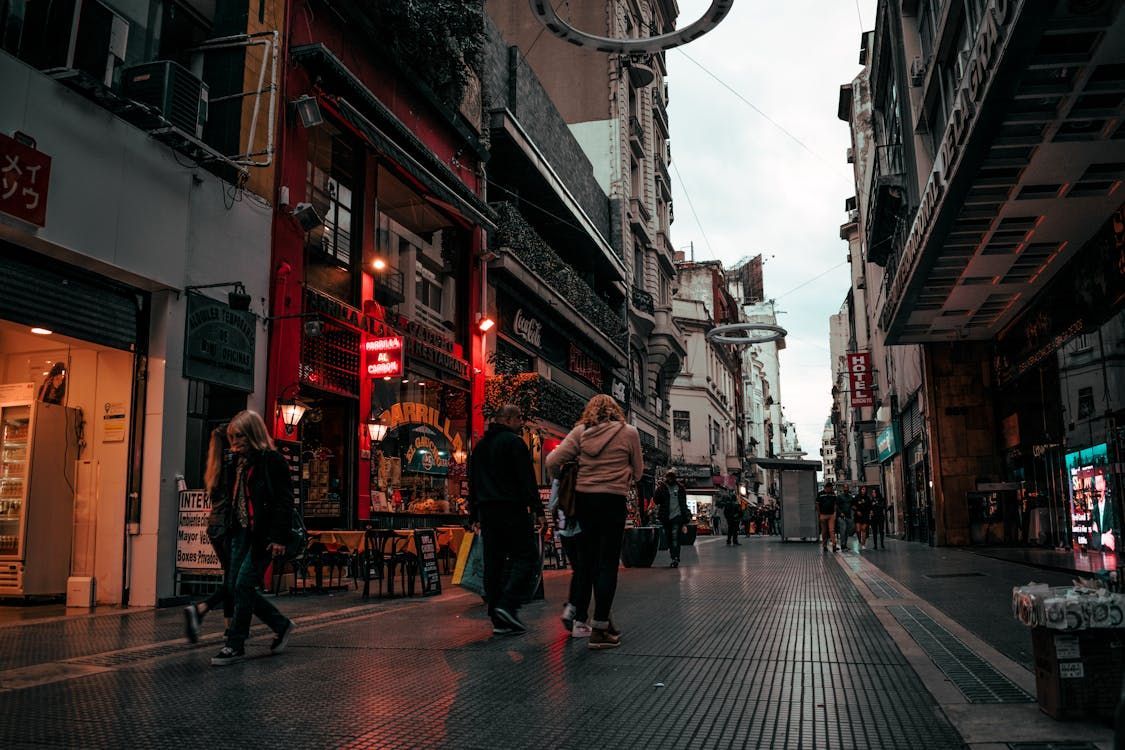 A group of people are walking down a narrow street in a city.