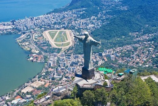 A statue of jesus is sitting on top of a hill overlooking a city.
