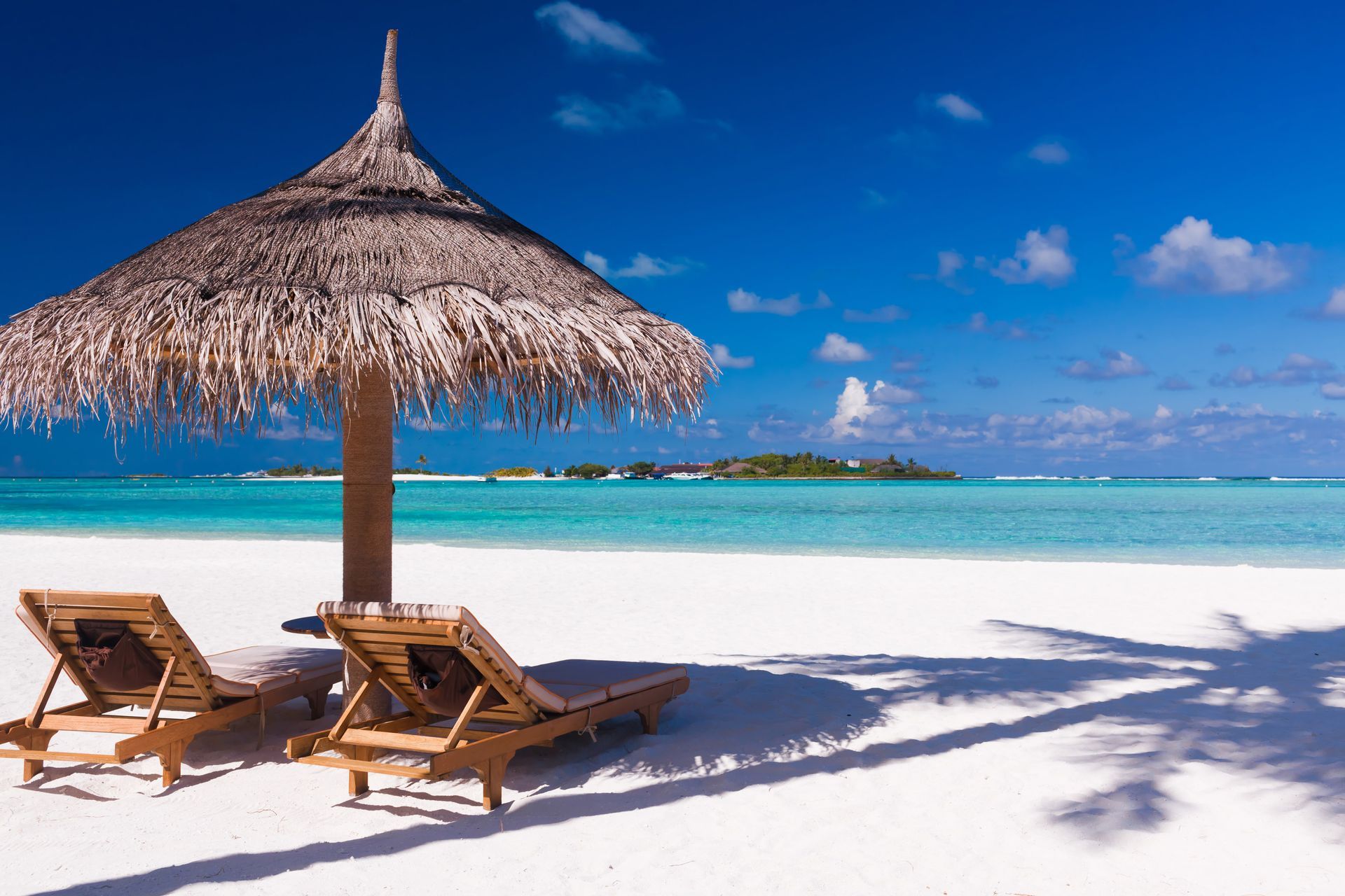 Sunbeds under a palapa on a tropical beach in Maldives, Indian Ocean.