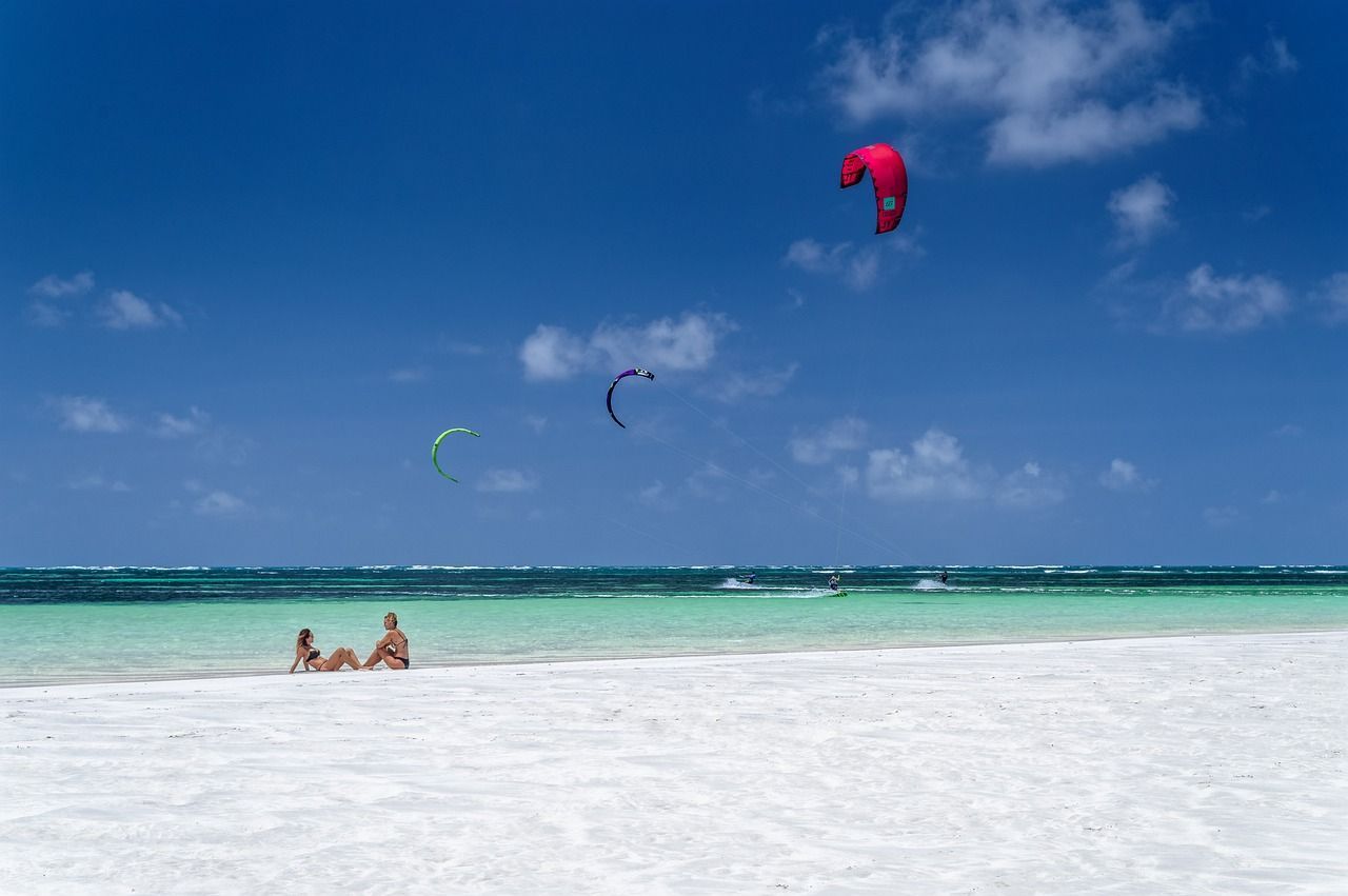 Tourists chilling and kitesurfing on a beach in Mombasa, Kenya.