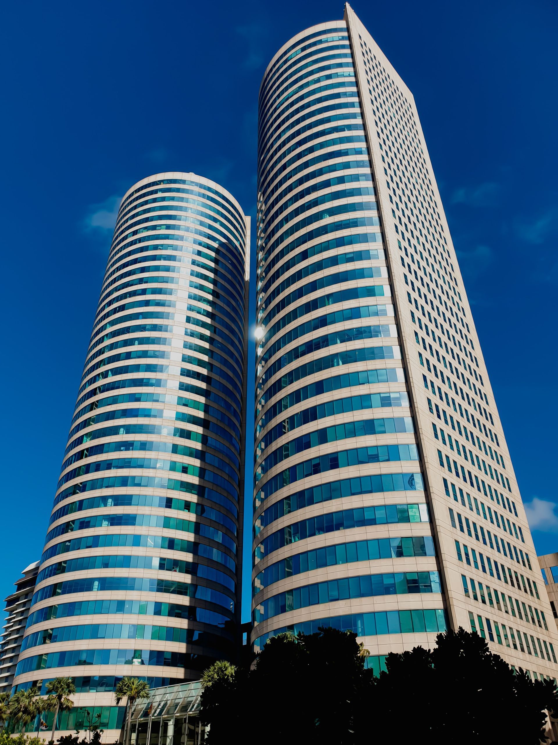 Two very tall buildings with a blue sky in the background
