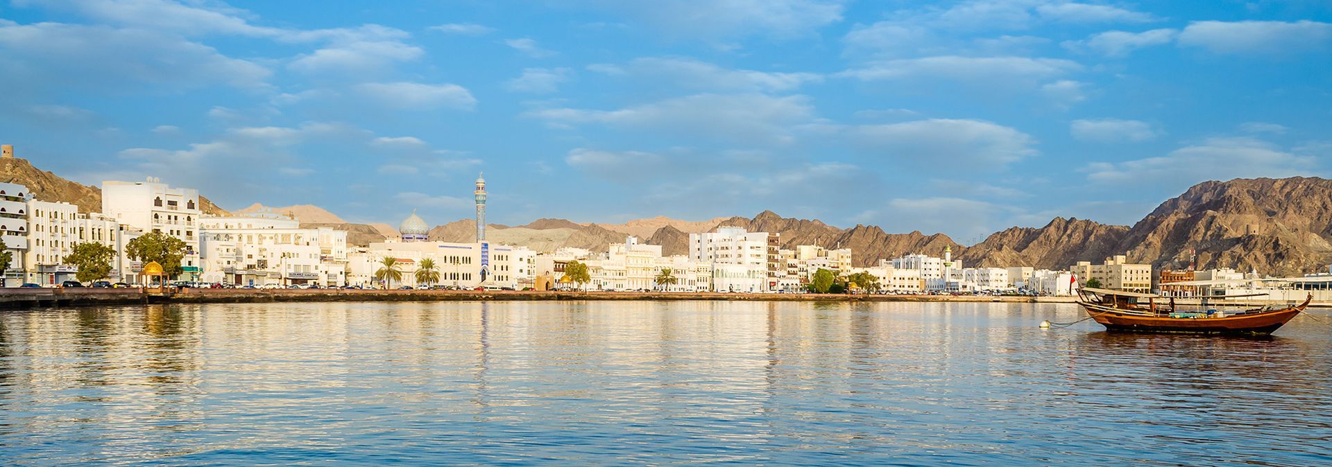 A boat is floating on top of a body of water in front of a city.
