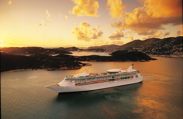 An aerial view of a cruise ship in the ocean at sunset