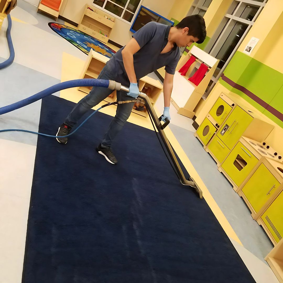 A man is using a vacuum cleaner to clean a blue rug
