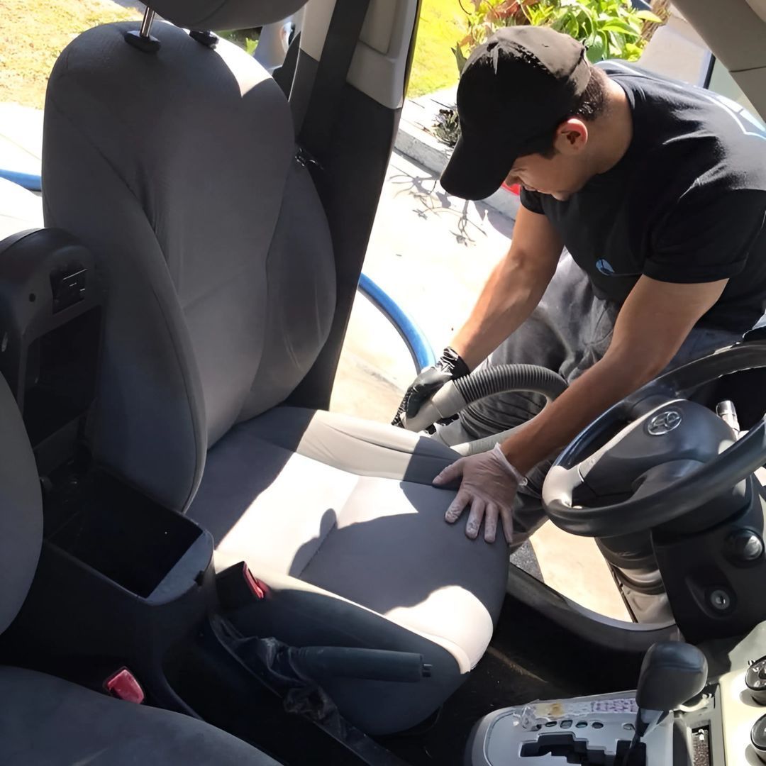 A man is cleaning the seats of a car