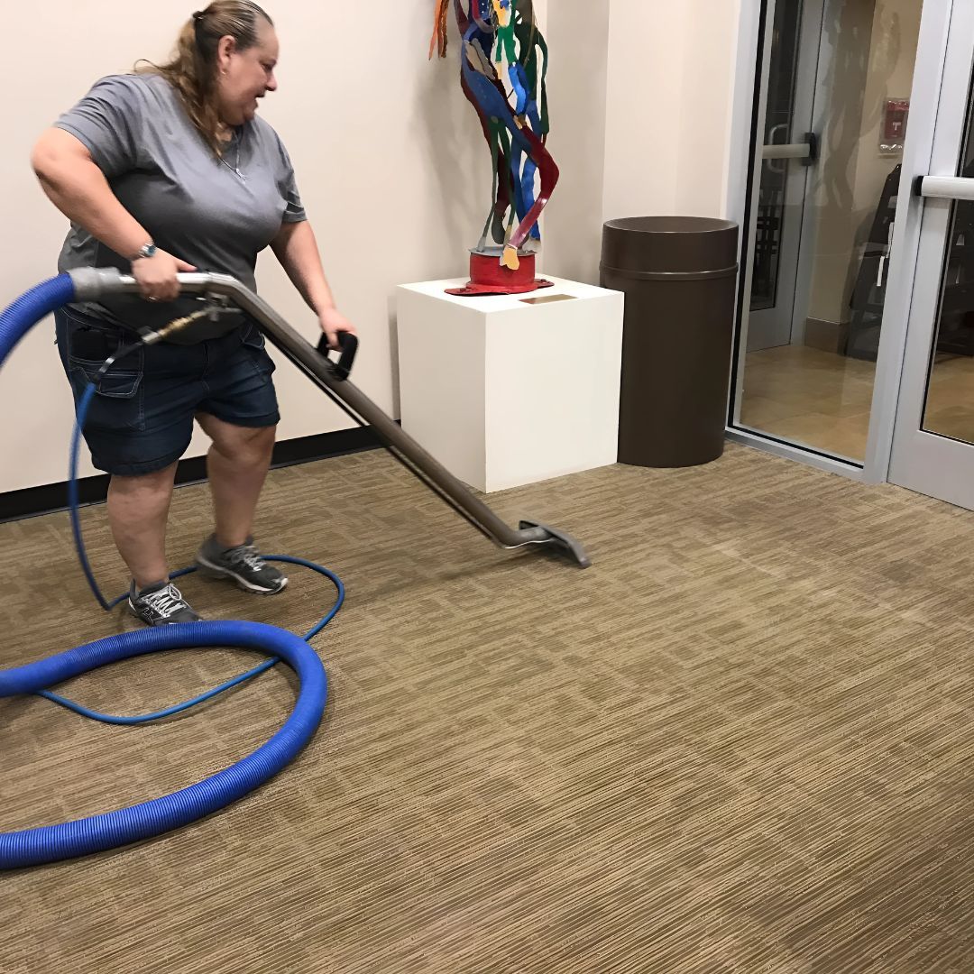 A woman is using a vacuum cleaner to clean a carpet.