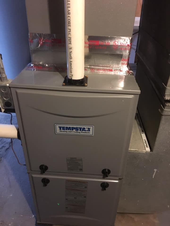 Gray Tempstar furnace with white PVC pipe, in a basement setting.