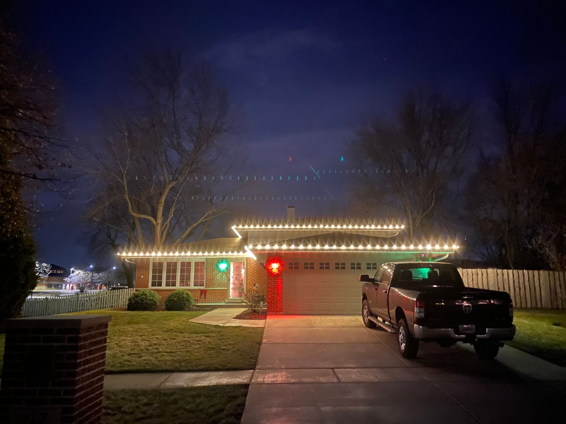 A truck is parked in front of a house decorated with christmas lights.