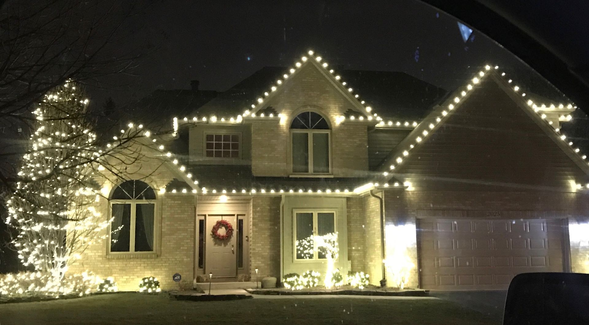A house with christmas lights on it is lit up at night.