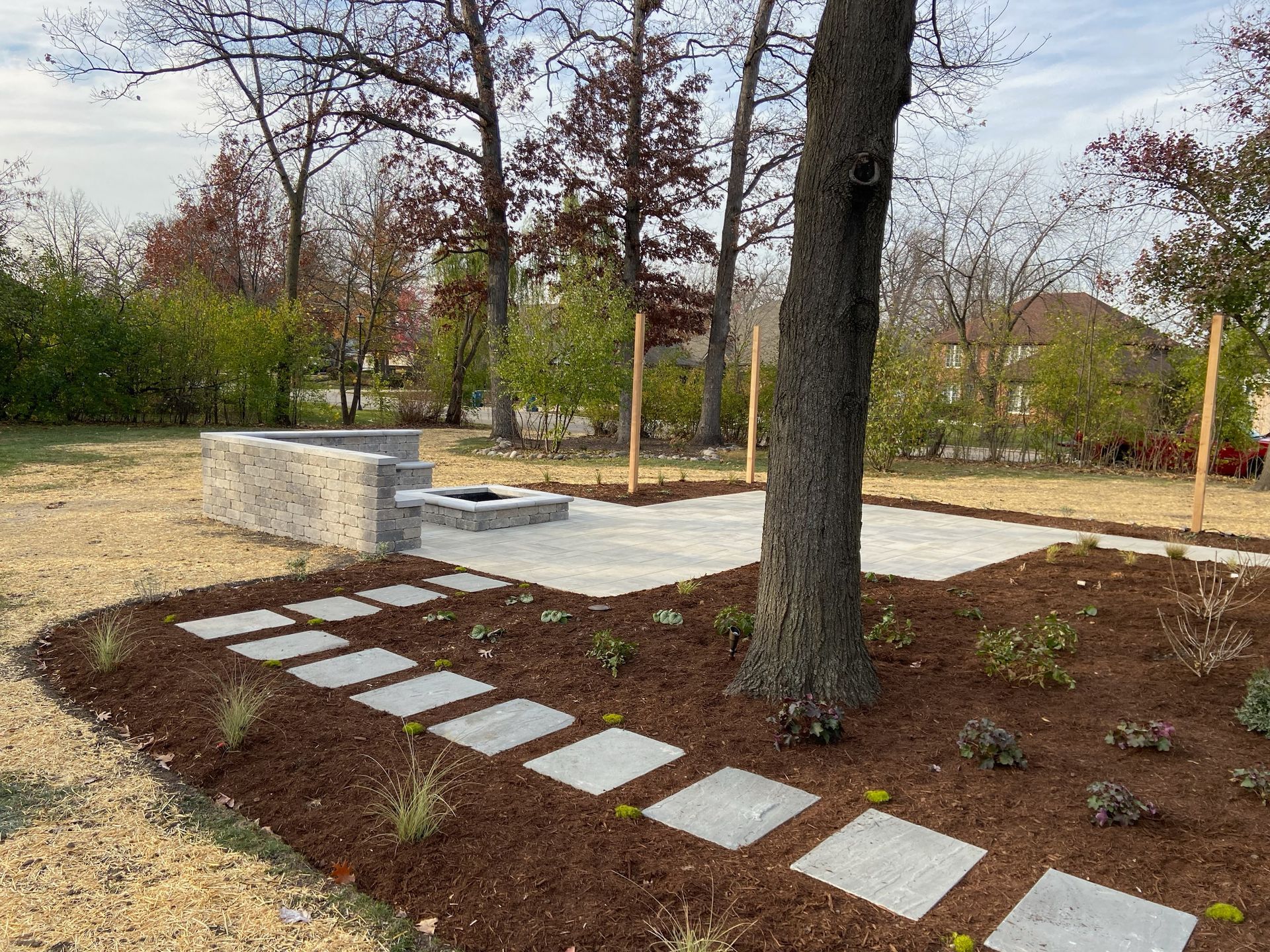 Stone patio with a fire pit, stepping stones, and mulch in a backyard setting.