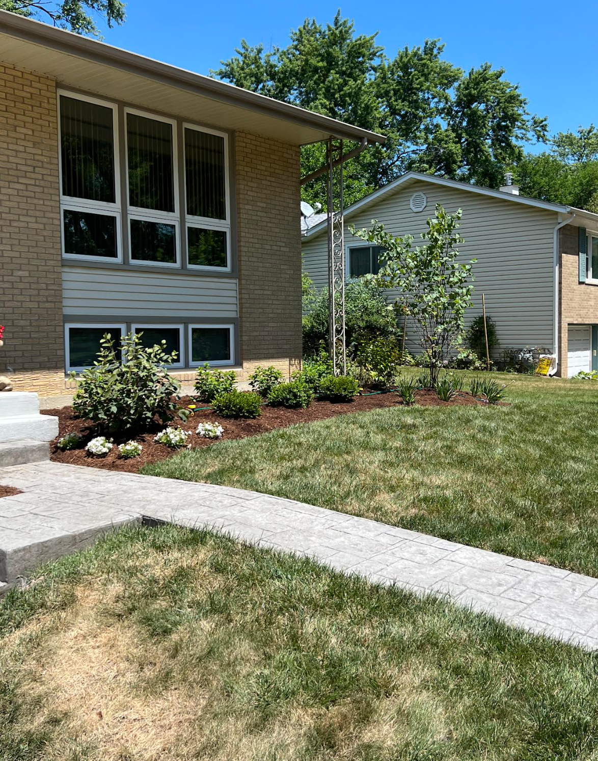A house with a lush green lawn and a sidewalk in front of it.