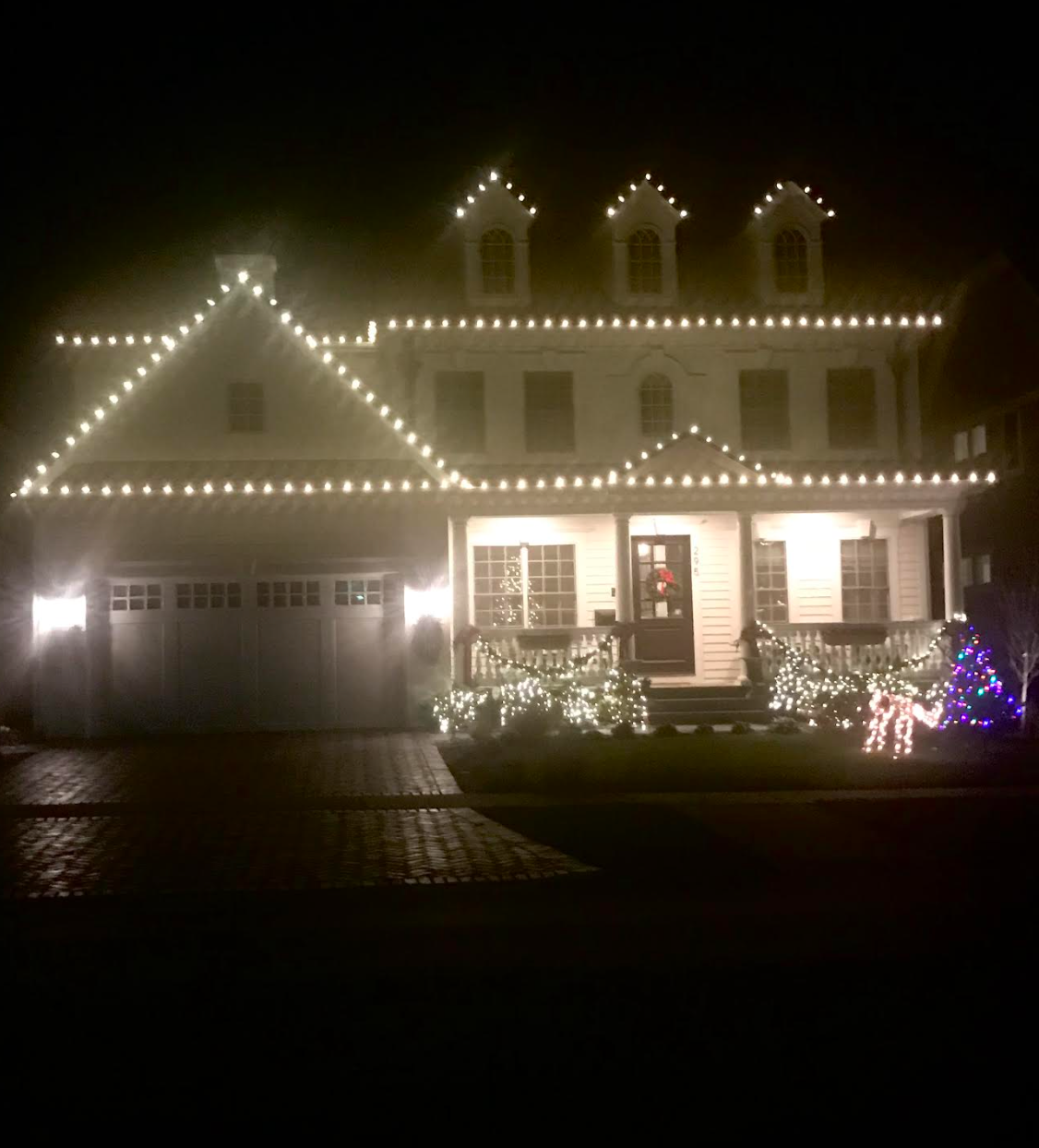 A house is lit up with christmas lights at night.
