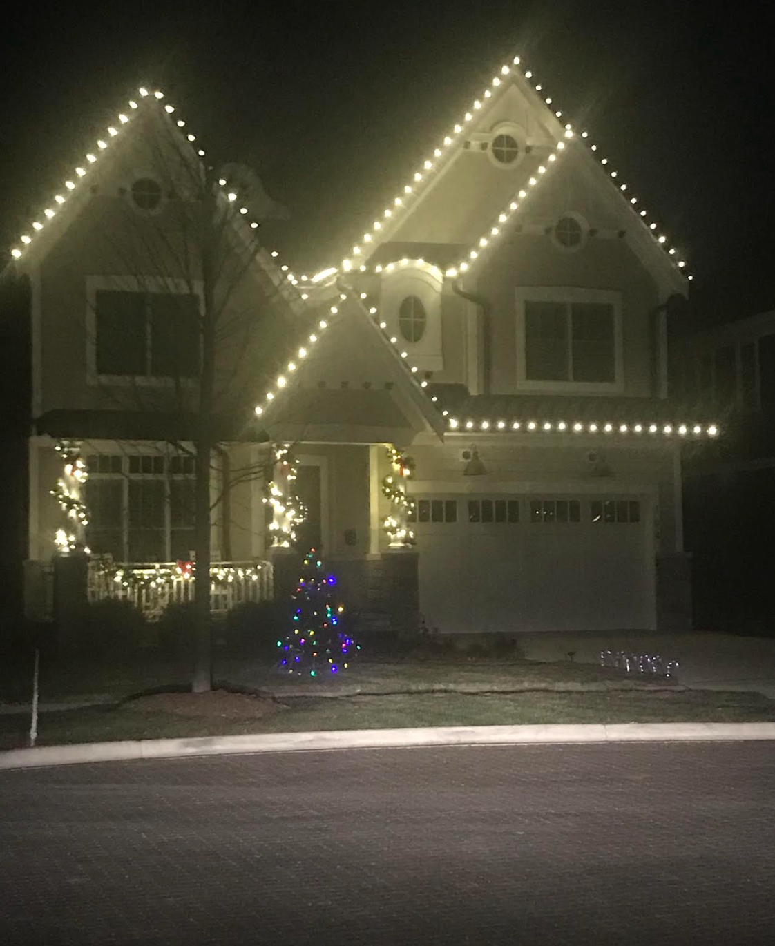 A house with christmas lights on it is lit up at night.