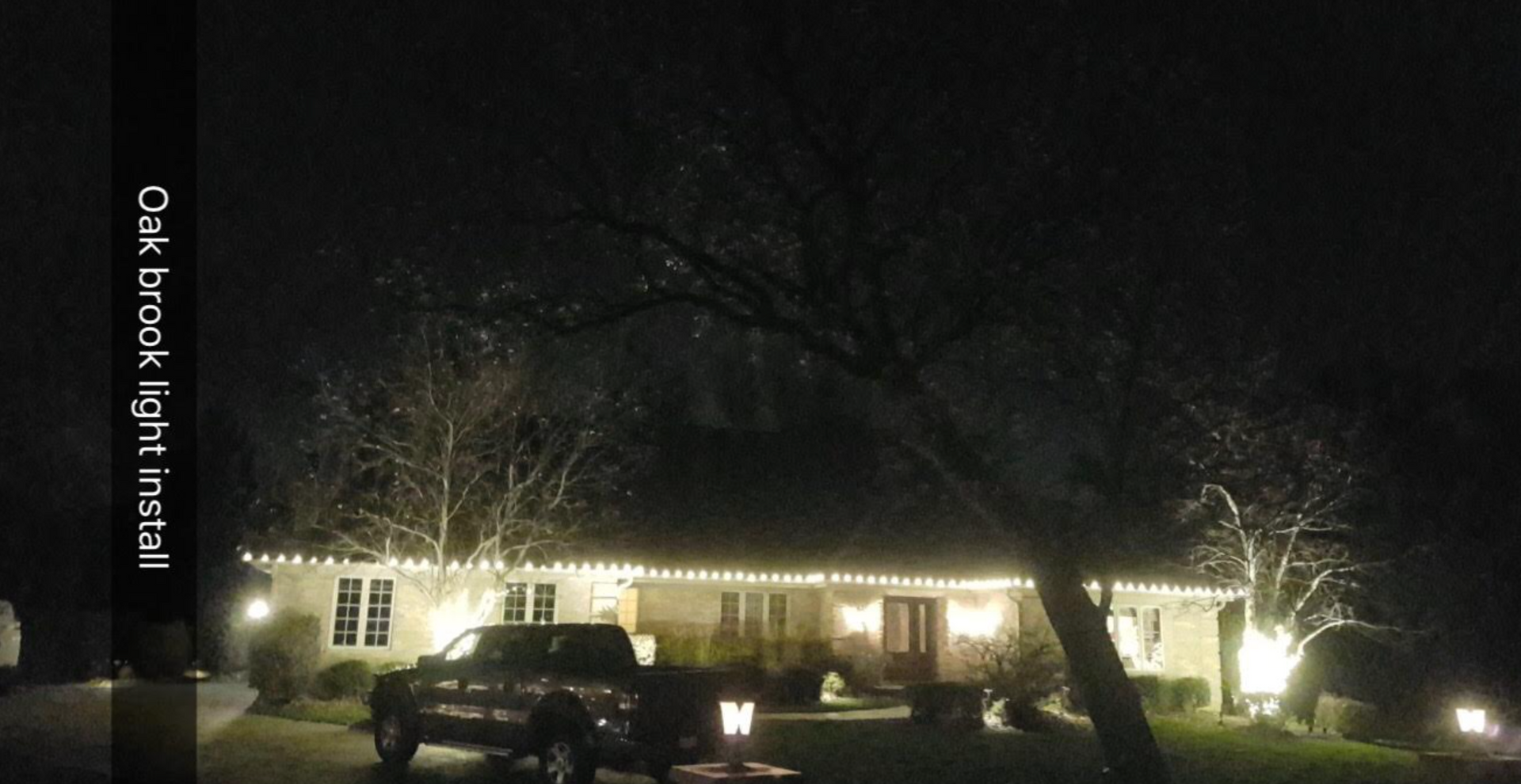 A truck is parked in front of a house that is lit up at night