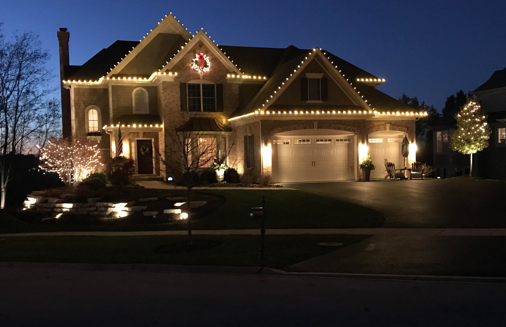 A large house with christmas lights on it is lit up at night.