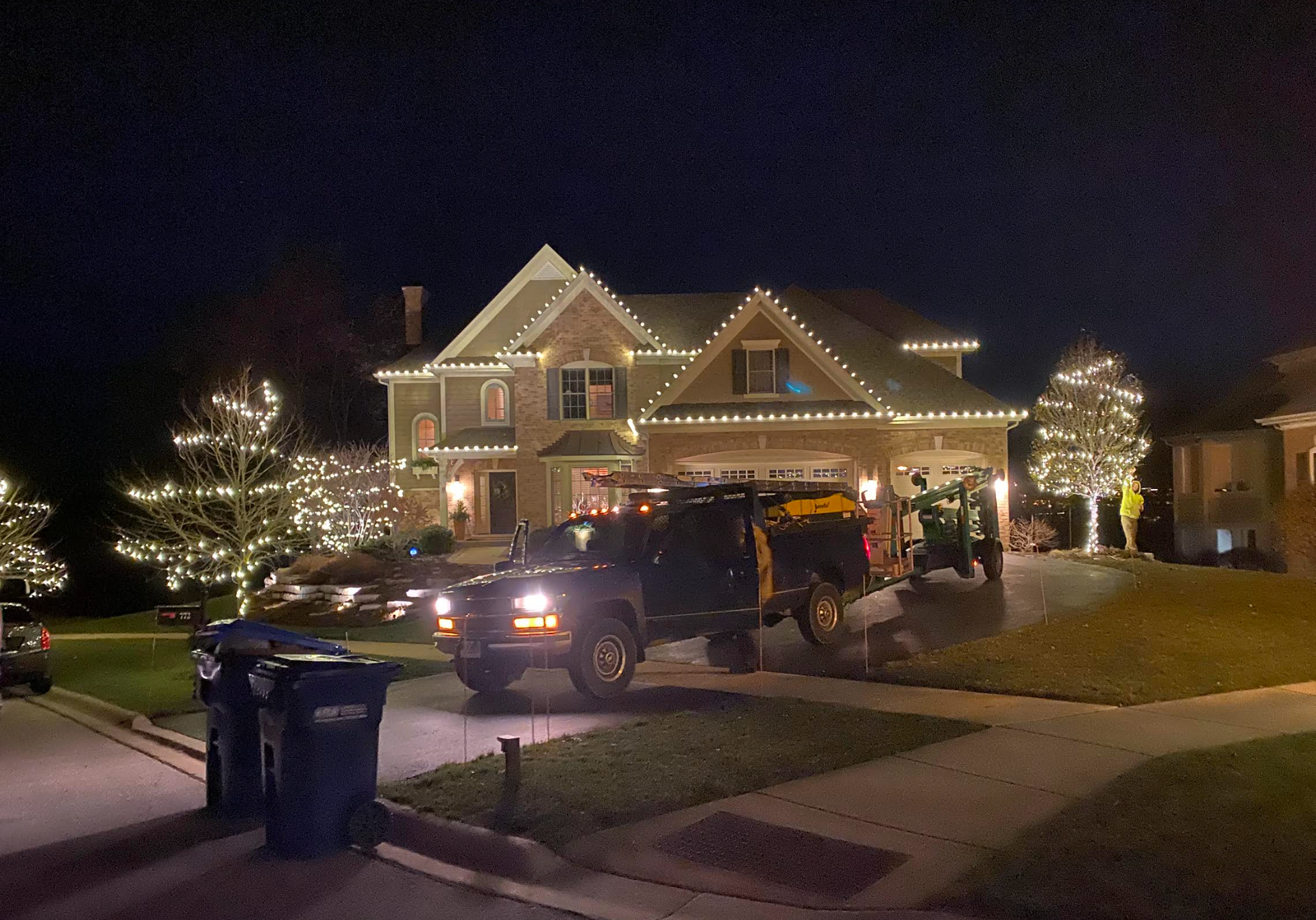 A truck is parked in front of a house decorated with christmas lights.
