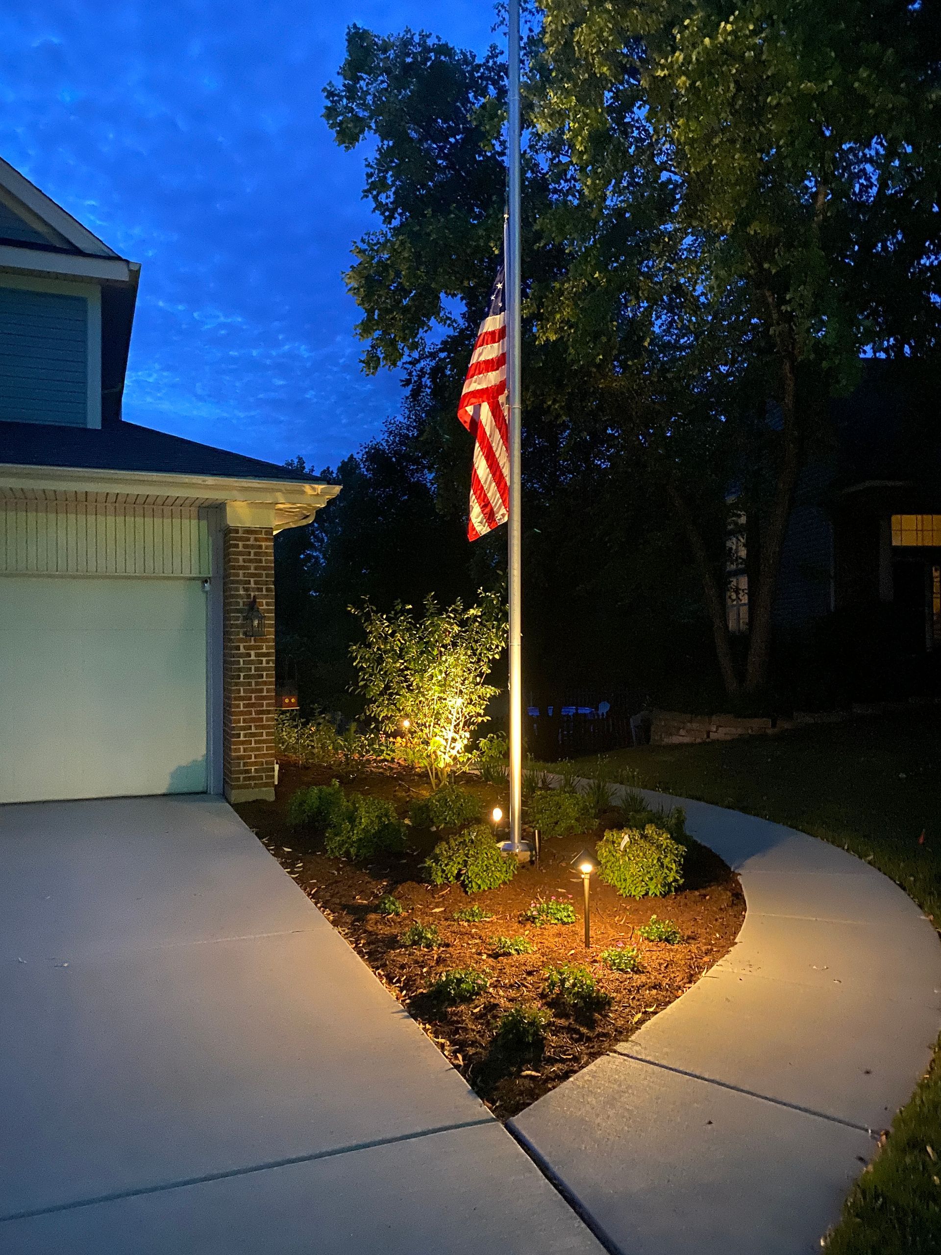 An american flag is flying in front of a house at night