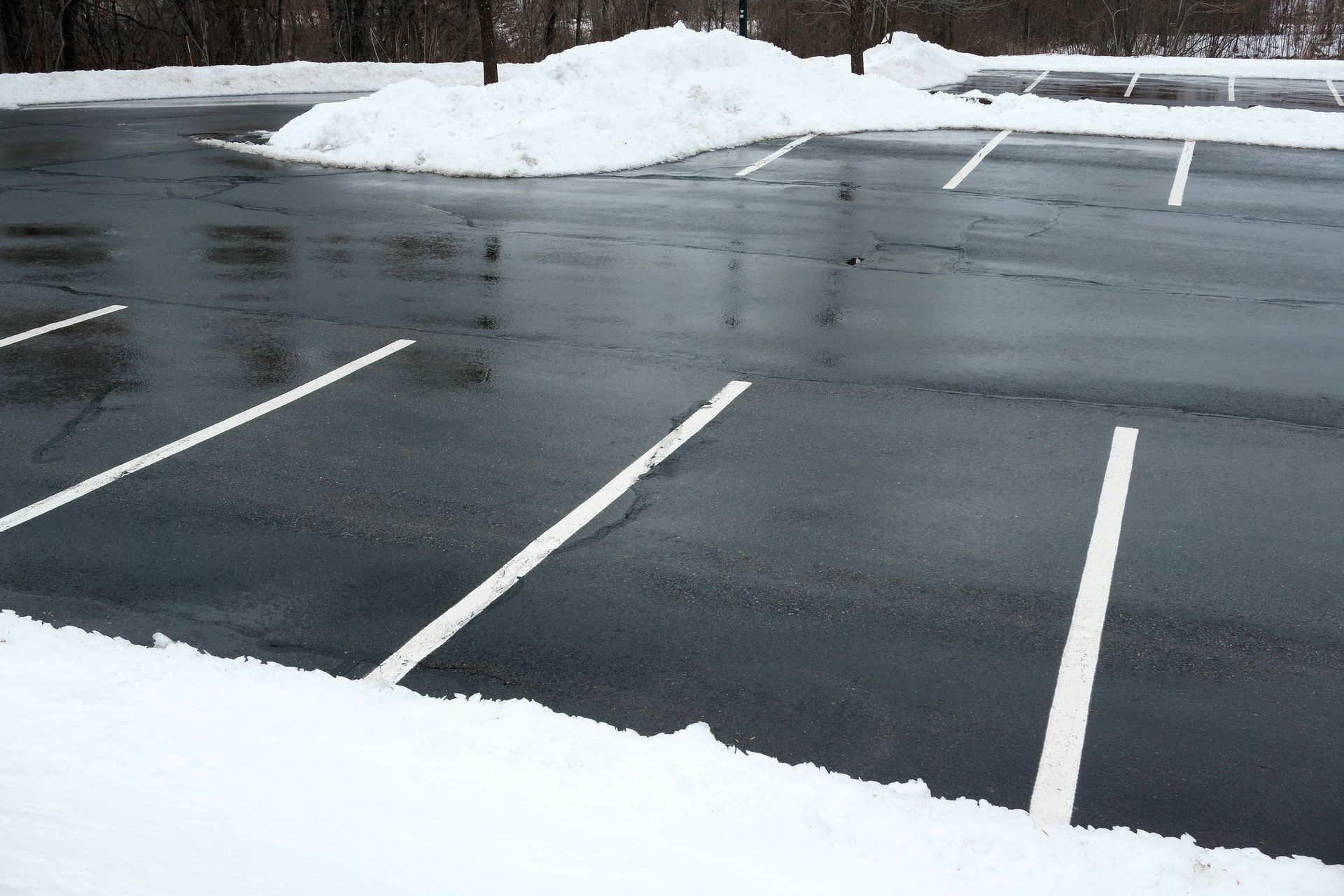 A parking lot with snow on the ground and white lines