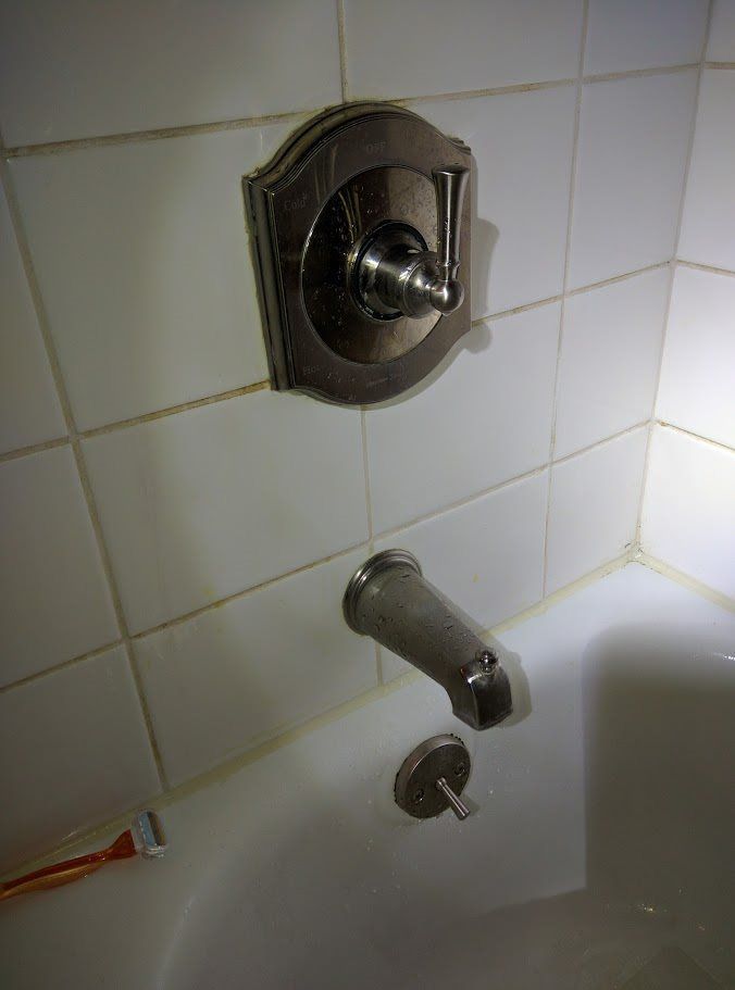 A bathtub with a faucet and a toothbrush in it.