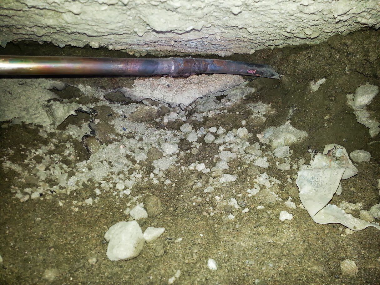 A pipe is laying on the ground next to a pile of rocks.