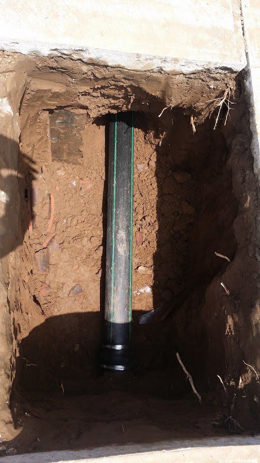 A green pipe is sitting in a hole in the ground.