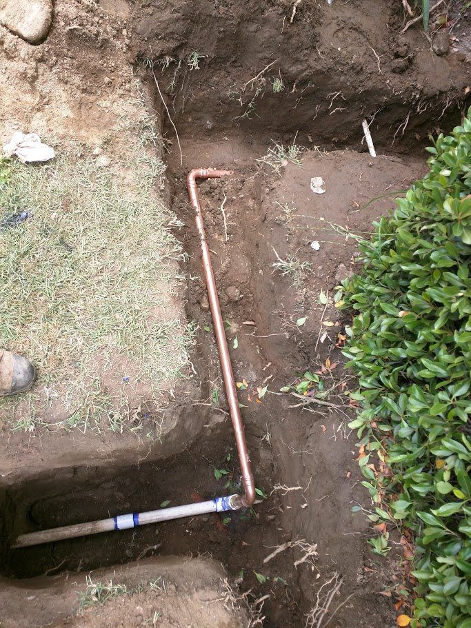 A copper pipe is being installed in a hole in the ground.