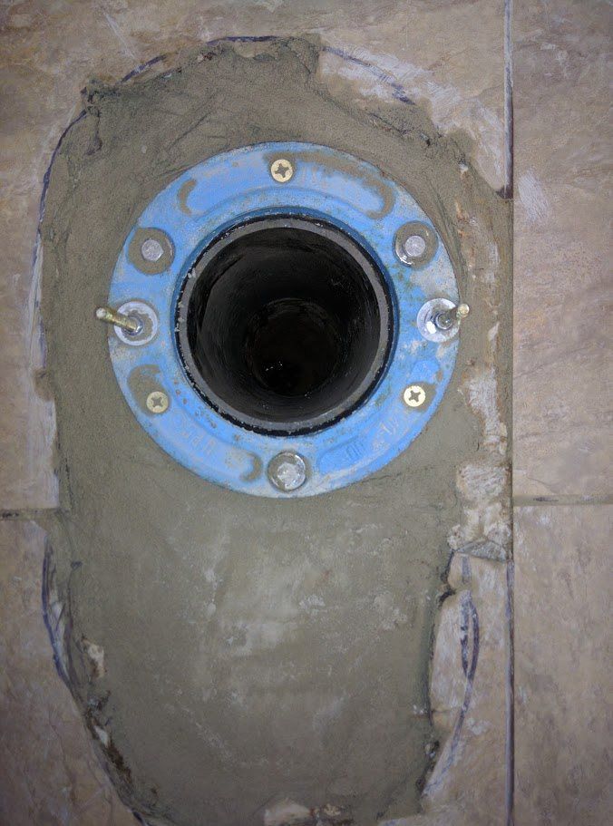 A toilet flange is being installed in a bathroom.