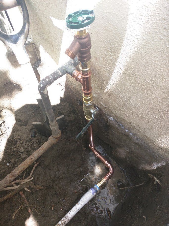 A copper pipe is connected to a valve on a wall.