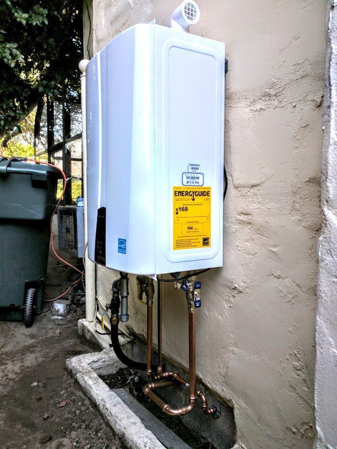 A white water heater is installed on the side of a building.