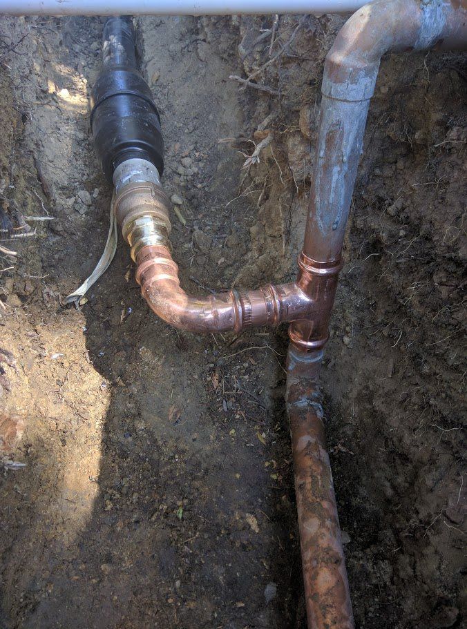 A close up of a copper pipe in the dirt.